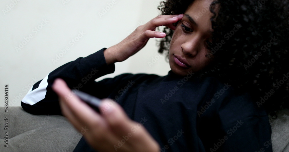 Black teen girl staring at her cellphone device watching online content