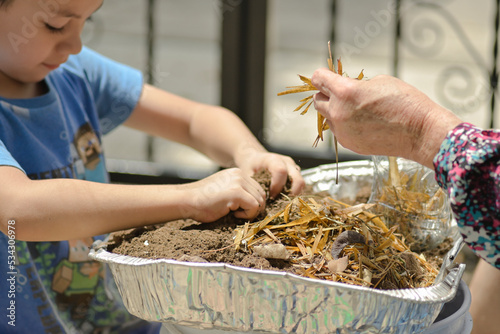 detail of the hands of a grandmother and child fertilizing soil to plant an urban garden