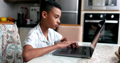 Black kid in front of laptop at home. Child browsing internet online computer © Marco