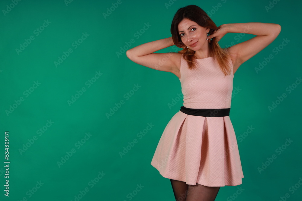 Beautiful slender woman in pink dress and black stockings on green background Beautiful slender woman in pink dress and black stockings on green background