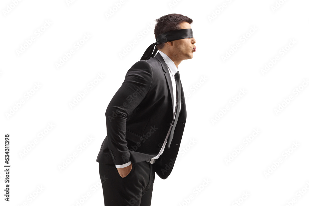 Profile shot of a young man in a suit with blindfold blowing a kiss
