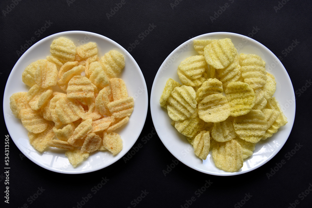 Delicious peppery corn chips on a white plate. Beer appetizer on a plate on a black background. Delicious peppery corn chips on a white plate. Beer appetizer on a plate on a black background.