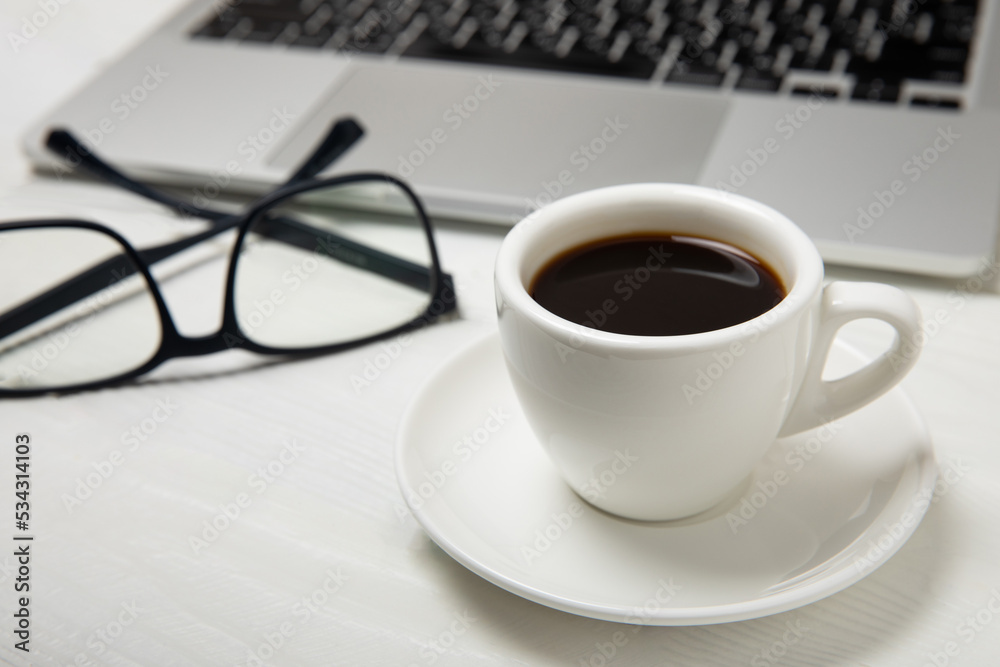 Top view of the office desk. Workspace with laptop, glasses and coffee cup on textural black background.Flat lay. Top view of the office desk. Workspace with laptop, glasses and coffee cup on textural black background.Flat lay.