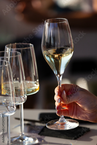 A right hand holds a crystal glass with white wine