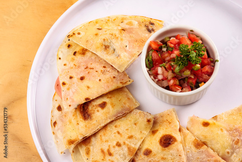 Mexican "synchronized" quesadilla with melted ham and cheese, bowl with pico de gallo sauce, Mexican food