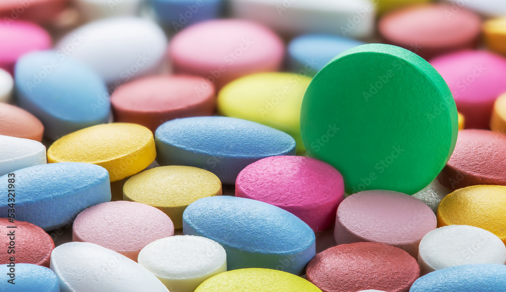 Selective focus on white pills on the background of pills of different colors. Antibiotic resistance. Tablets from antimicrobial viruses. Pharmaceutical industry.. Selective focus on white pills on the background of pills of different colors. Antibiotic resistance. Tablets from antimicrobial viruses. Pharmaceutical industry..