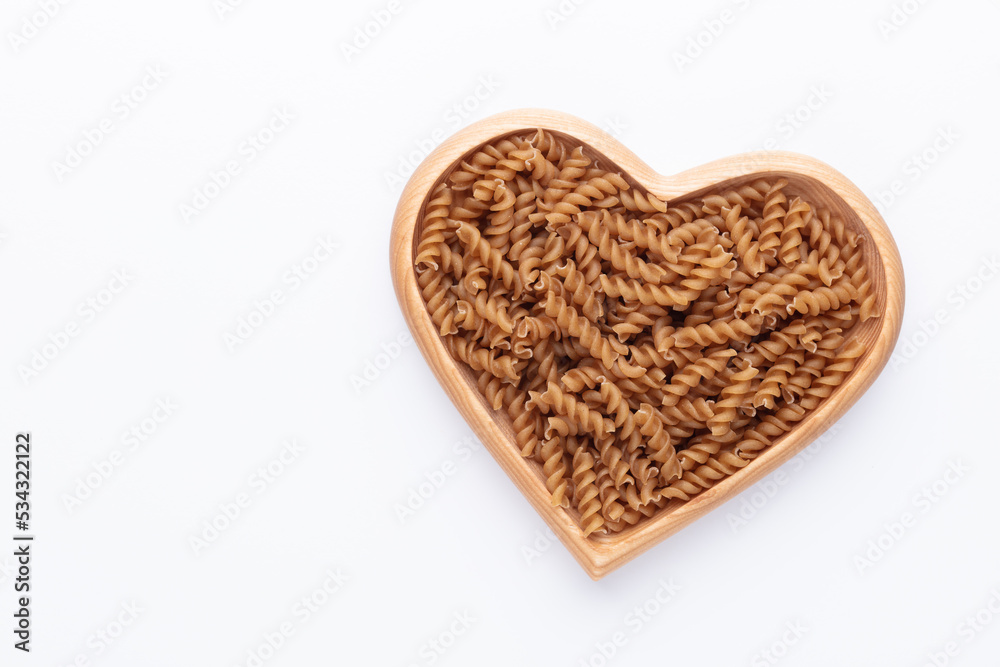 Whole grains fusilli pasta in a heart shaped wood bowl. Whole grains fusilli pasta in a heart shaped wood bowl.