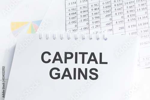Capital gains text concept on notepad on the table among documents, business concept