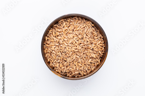 Wheat grains and wooden bowl on white background.