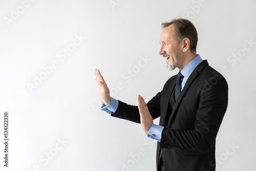 Portrait of stressed mature businessman making stop gesture. Terrified senior Caucasian manager wearing three piece suit protecting himself from problems. Fear and problems concept