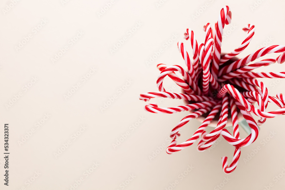Christmas candy canes in a cup, pastel background. Christmas candy canes in a cup, pastel background.