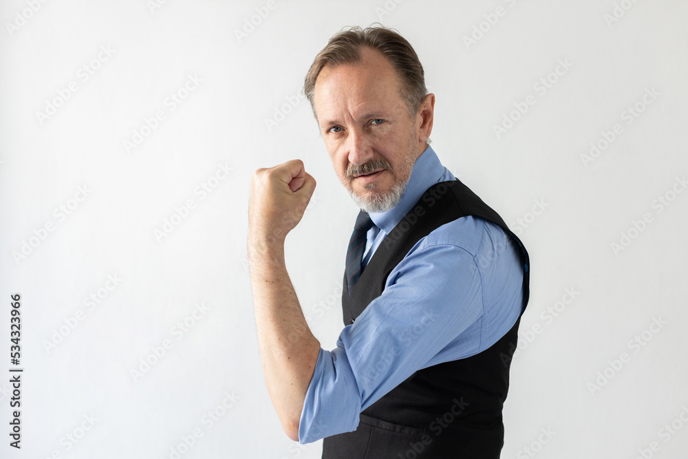 Portrait of confident mature businessman showing muscle or fist and looking at camera. Senior Caucasian manager wearing formalwear showing his power or authority. Strength and confidence concept Portrait of confident mature businessman showing muscle or fist and looking at camera. Senior Caucasian manager wearing formalwear showing his power or authority. Strength and confidence concept