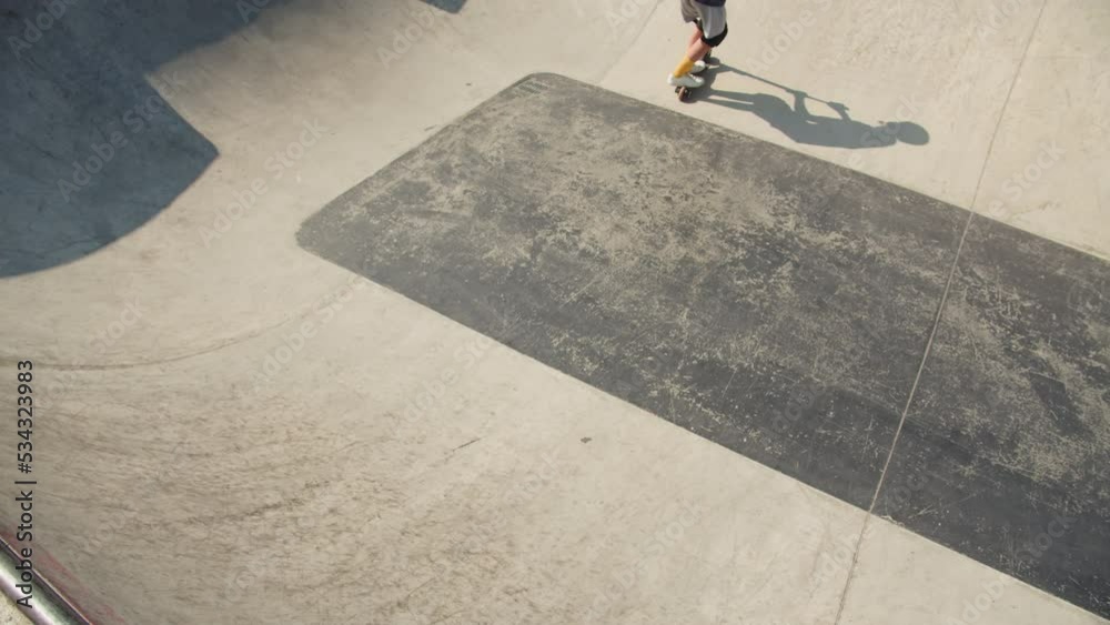 Man making trick on kick scooter in concrete bowl, air extreme in skate park, grab and barspin jump, young skater boy. 