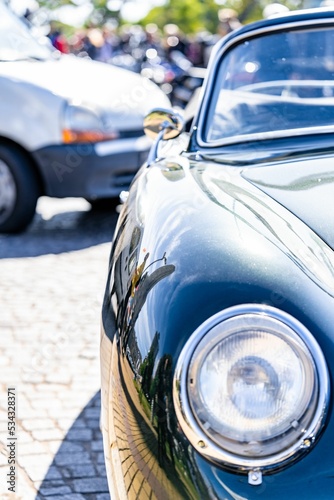 Closeup vertical shot of the Old green Porche car on a sunny day