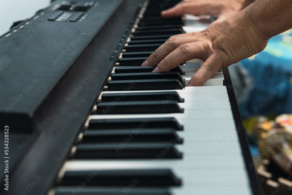 Image of the hands of an unrecognizable person playing the keys of the electronic digital piano.