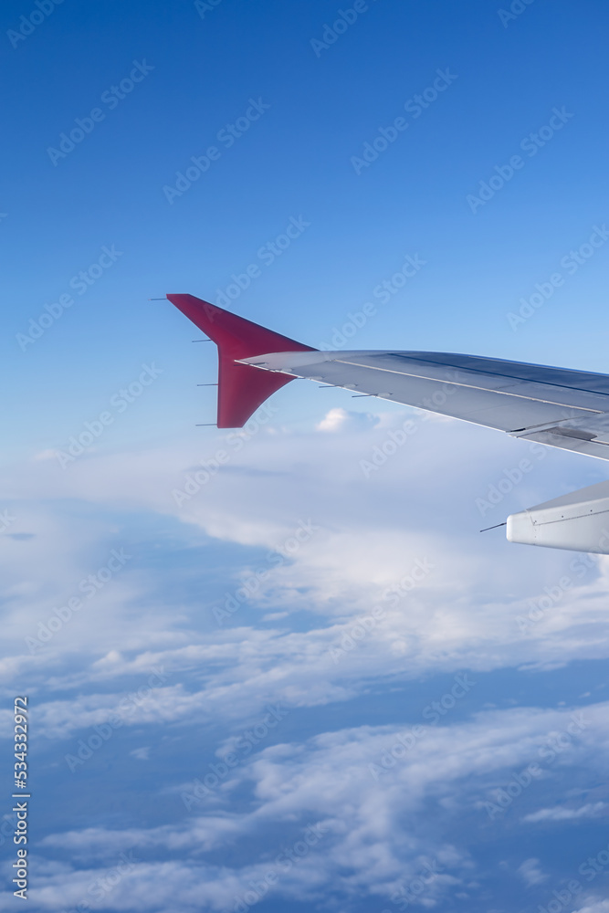 vertical photo the wing of a flying aircraft against the background of clouds vertical photo the wing of a flying aircraft against the background of clouds
