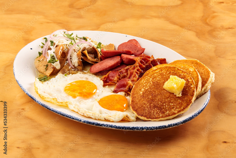 Full American breakfast with eggs, bacon, pancakes, sausage and chilaquiles, food Full American breakfast with eggs, bacon, pancakes, sausage and chilaquiles, food