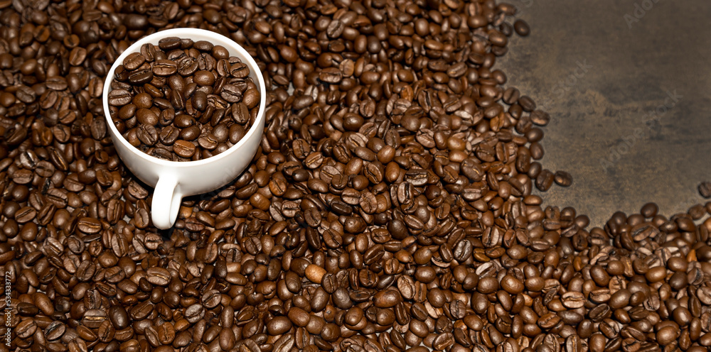 Naklejka premium Spilled coffee beans, a cup of coffee and coffee beans on the table.