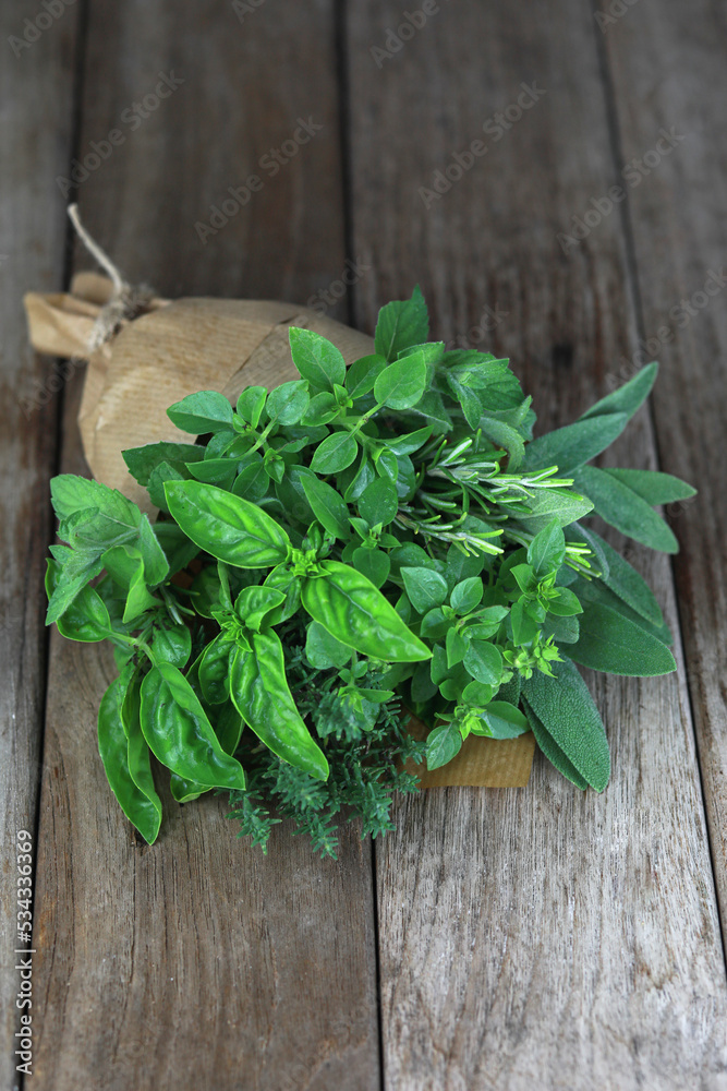 Fresh herb bouquet with rosemary, thyme, mint, sage and different kind of basil. Farm-to market herbs and sprigs tied with string in a bouquet on wooden background. Fresh herb bouquet with rosemary, thyme, mint, sage and different kind of basil. Farm-to market herbs and sprigs tied with string in a bouquet on wooden background.