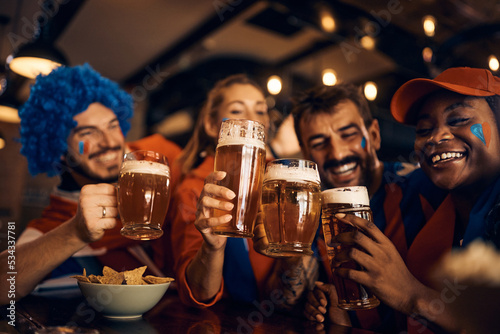 Close up of soccer fans celebrate their team's victory and toast with beer in pub. © Drazen