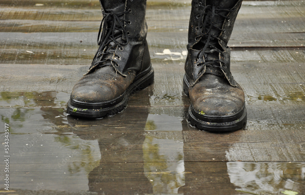 old boots with autumn leaf on wet wooden floor old boots with autumn leaf on wet wooden floor