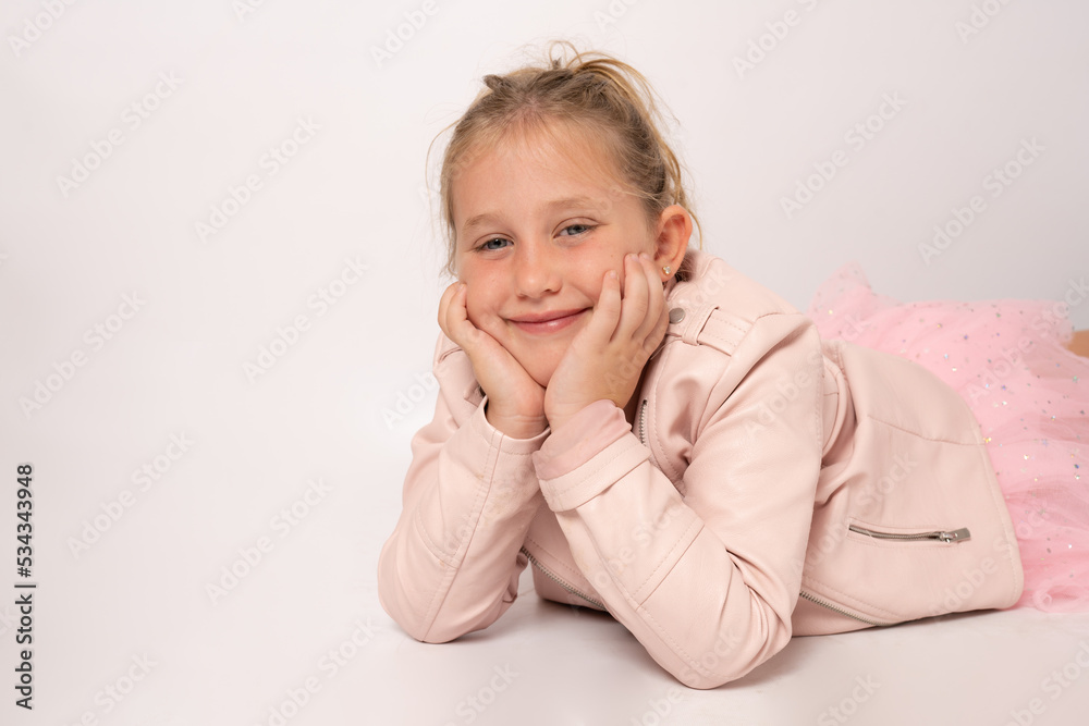 Portrait of a happy smiling cute little girl lying on the floor isolated on white background.