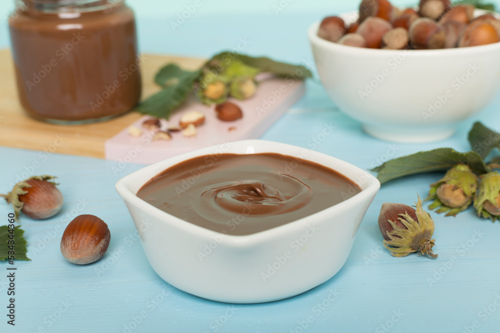 Hazelnut cream with nuts and green leaves on wooden table Hazelnut cream with nuts and green leaves on wooden table
