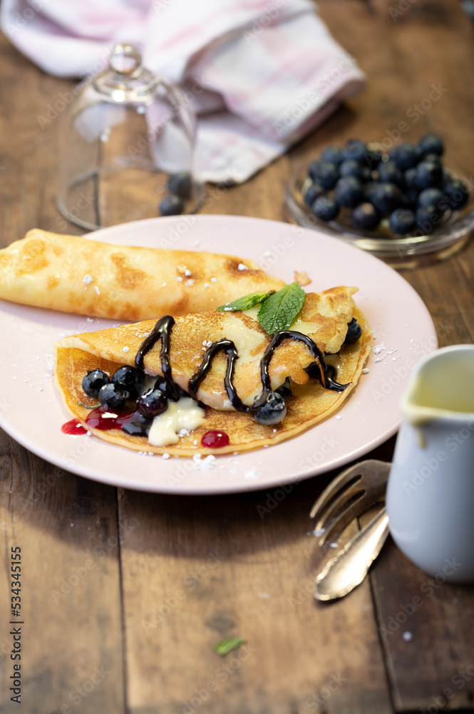 Leckere Pfannkuchen mit Beeren und Soße auf rustikalen Tisch Leckere Pfannkuchen mit Beeren und Soße auf rustikalen Tisch