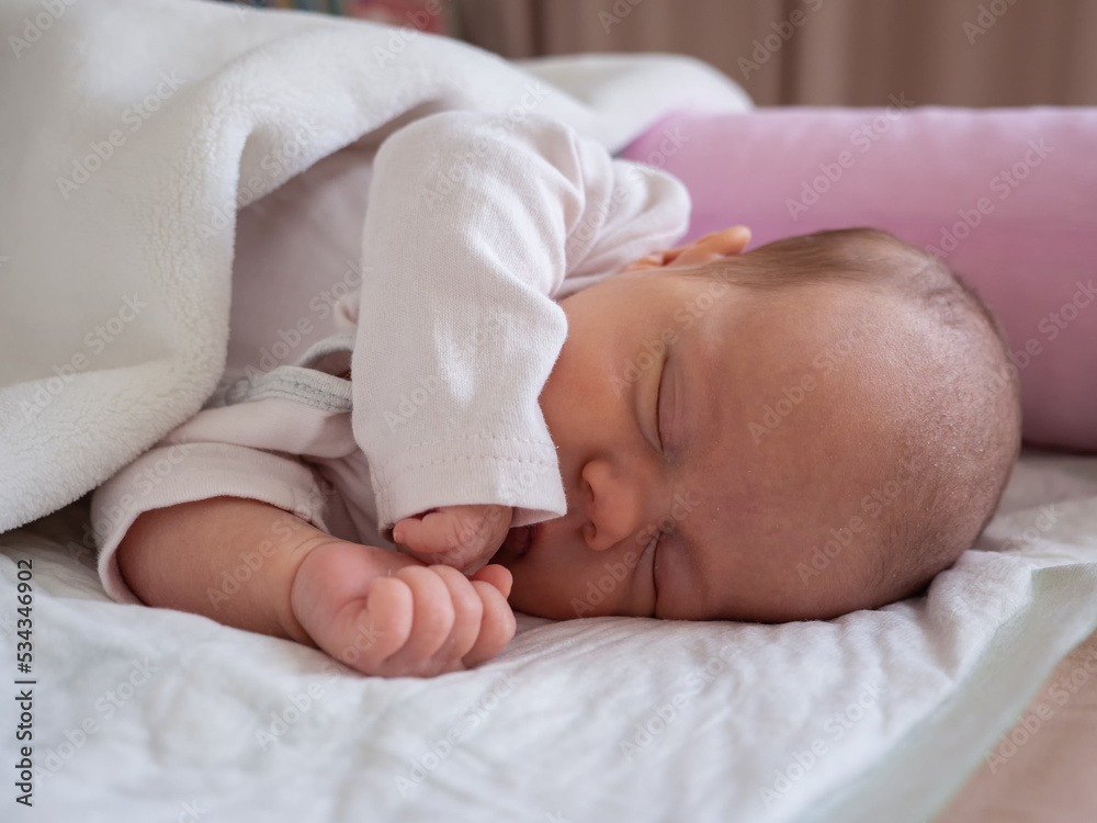 cute little newborn baby girl peacefully sleeps in the nursery on a white cotton bed cute little newborn baby girl peacefully sleeps in the nursery on a white cotton bed