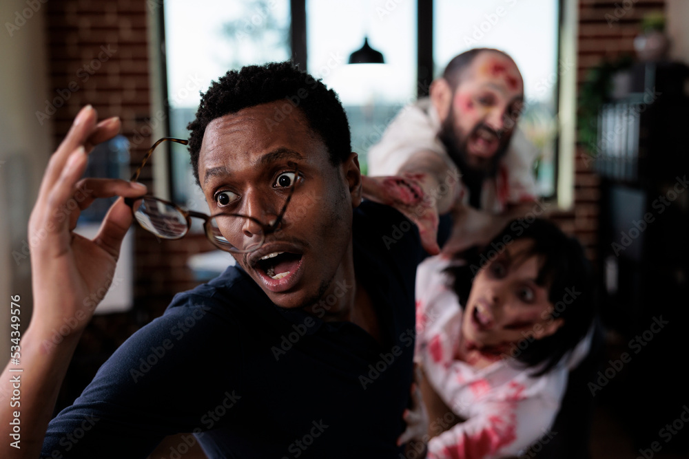 Φωτογραφία Frightened fearful man running from zombies, trying to escape from angry evil corpses with bloody wounds and scars