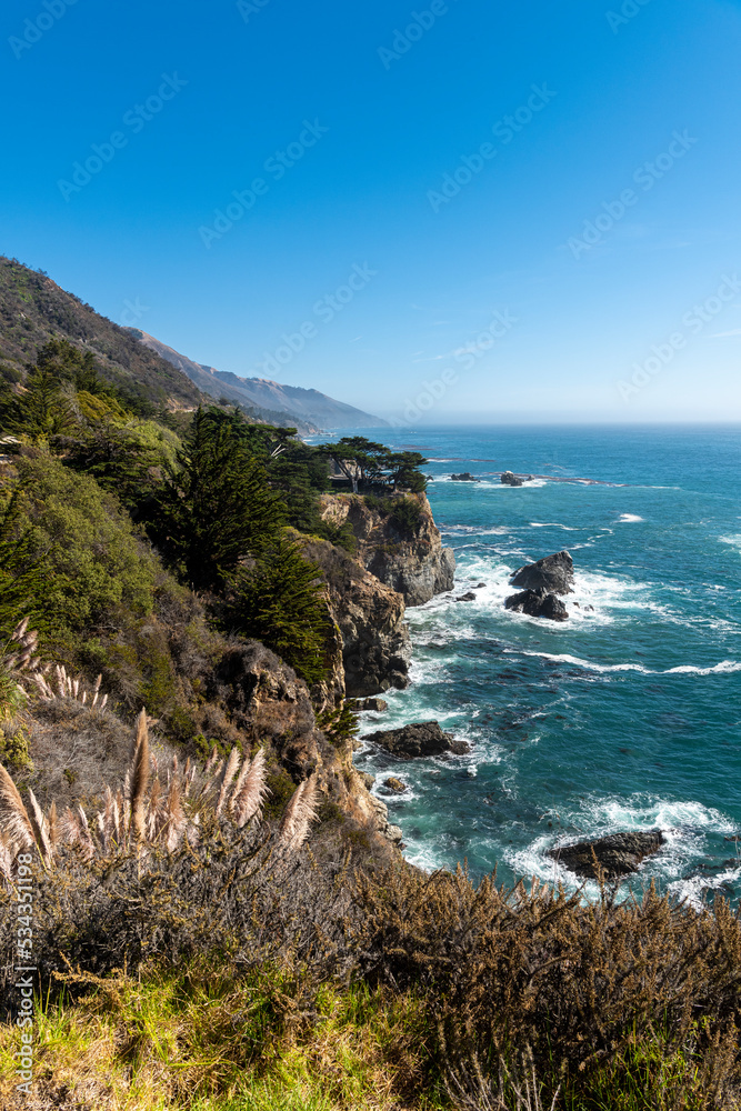 The rugged coastline of Big Sur with wisps of fog drifting into the hills.