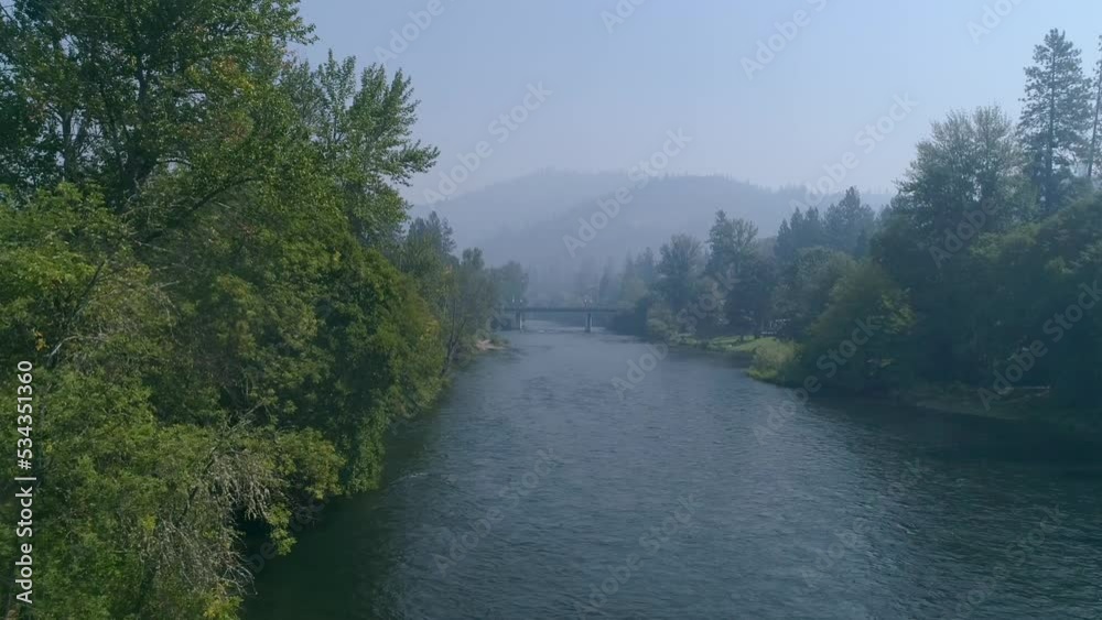 Moving drone shot of trees on the bank of the Rogue River on a smoky, summer day. Moving drone shot of trees on the bank of the Rogue River on a smoky, summer day.