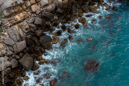top view of the rocky coast in a storm, azure water and waves near the shore