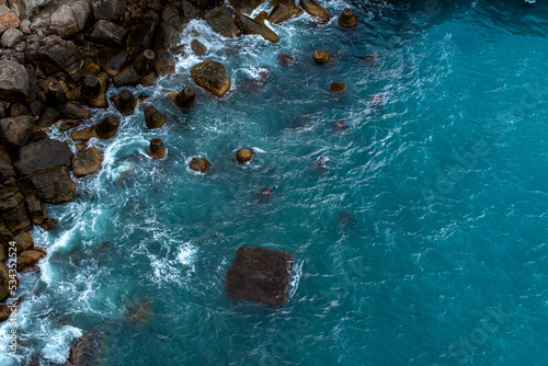 top view of the rocky coast in a storm, azure water and waves near the shore