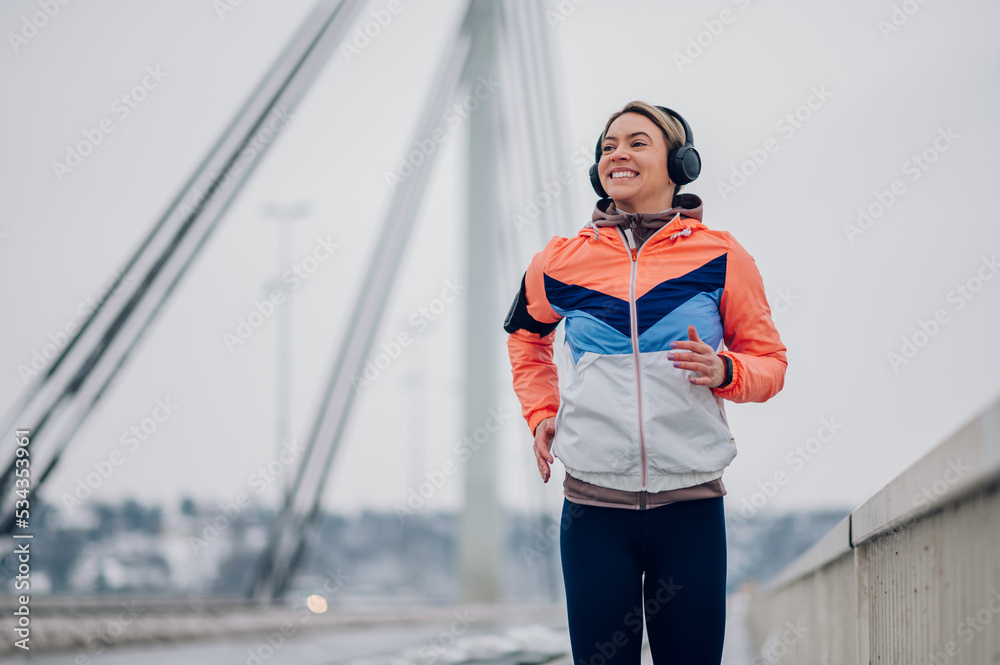 Obraz premium Woman running on the bridge at winter and snow.