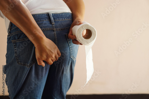 Closeup man hands hold his bottom and roll of tissue paper. Concept : getting diarrhea. Need to go to the toilet, suffer from food poisoning. Using tissue paper for hygiene. Health problems. 