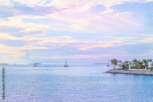 A picturesque look of Key West jutting out in the water sailboats and houses at sunset.