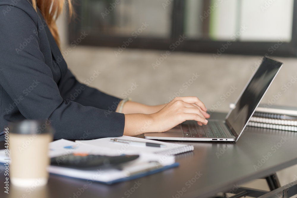 Using laptop, Young pretty asian stock manager checking list of product and working at workstation. Using laptop, Young pretty asian stock manager checking list of product and working at workstation.