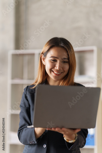 Young pretty asian stock manager checking list of product and working at workstation, using laptop. Free Download Young pretty asian stock manager checking list of product and working at workstation, using laptop. - GFXLoad