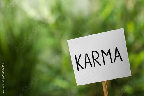Sign with word Karma on blurred background, closeup. Space for text © New Africa