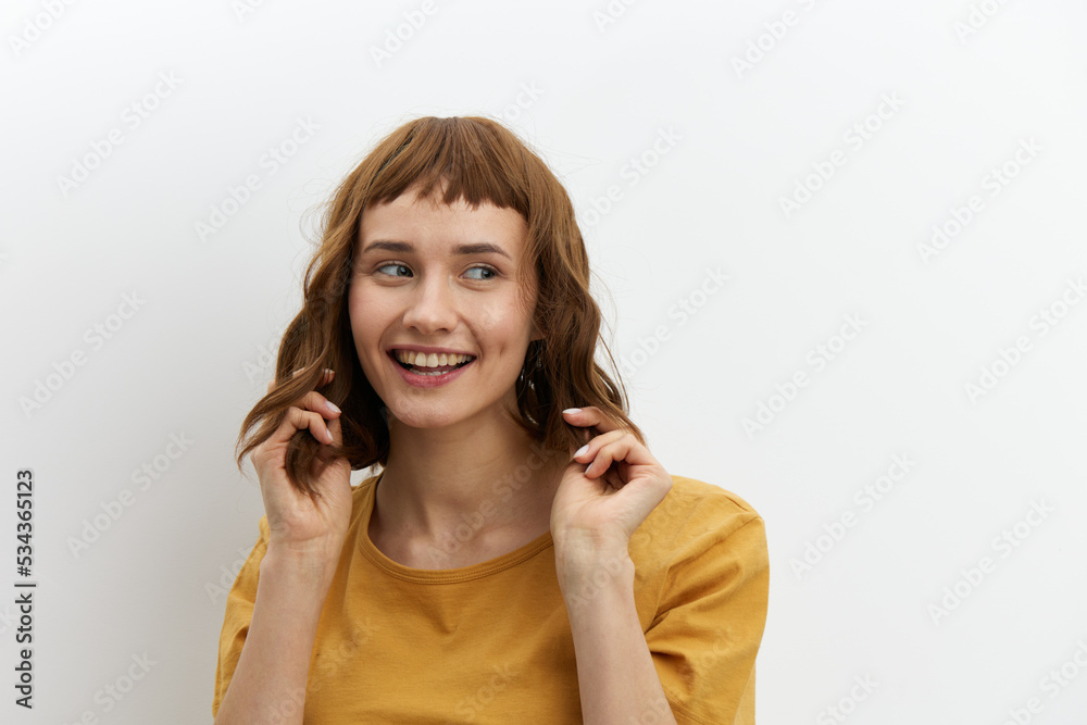 a sexy, attractive woman with short red hair stands holding them on both sides with her hands and looks into the camera a sexy, attractive woman with short red hair stands holding them on both sides with her hands and looks into the camera