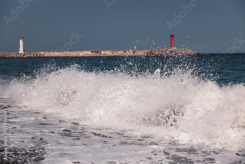 the angry waves and the red lighthouse along the coast