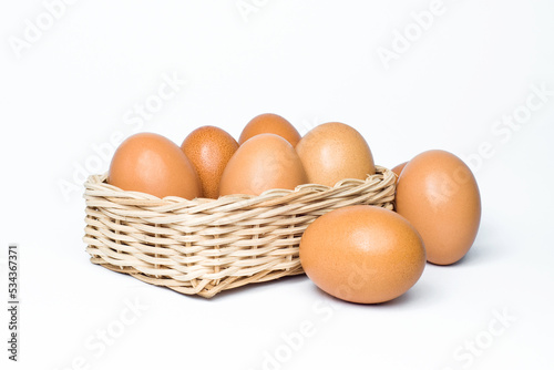 eight chicken eggs in a rattan basket on white background