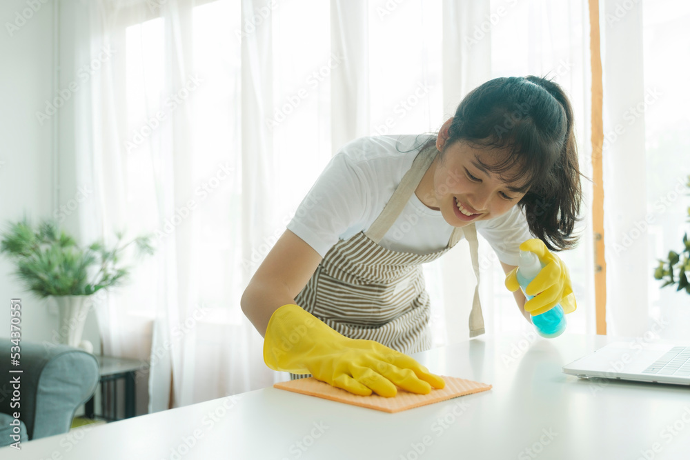 Young woman cleaning table wearing gloves at home. Young woman cleaning table wearing gloves at home.