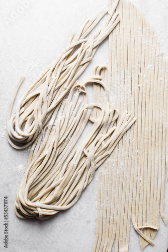 Fresh homemade noodles on white marble board, floured fresh noodles