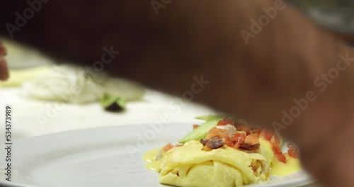 Closeup shot of chef adding finishing touches to omelet dish.
