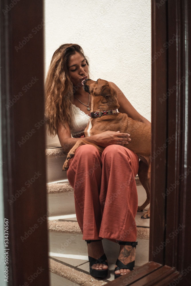 Beautiful young latina hugging her dog.