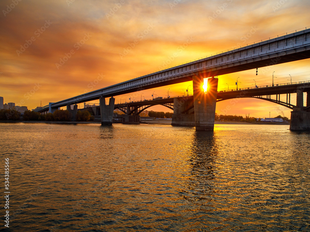 The world's largest metro bridge on v-shaped concrete supports across the Ob river and road October bridge, the big city Novosibirsk at sunset The world's largest metro bridge on v-shaped concrete supports across the Ob river and road October bridge, the big city Novosibirsk at sunset