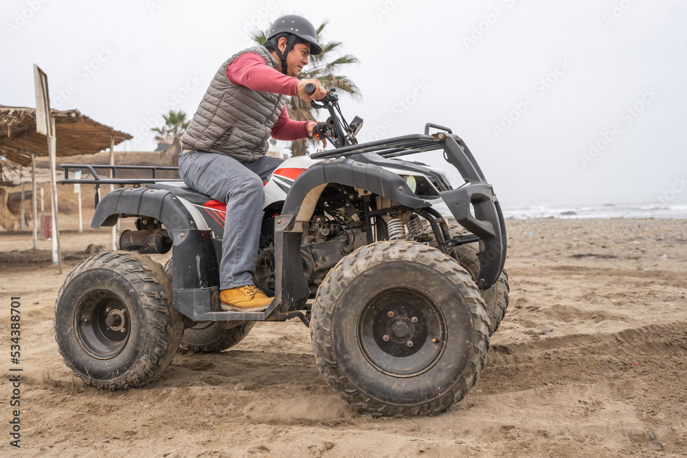 Fototapeta premium Man driving a quad bike along a beach