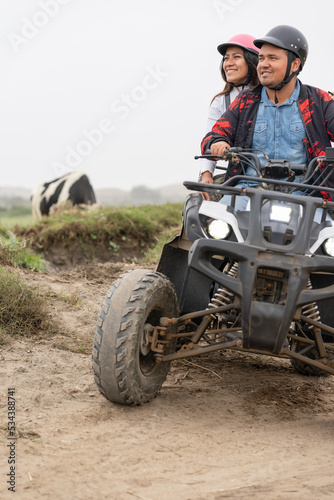 Vertical photo of a couple on a quad in a rural road
